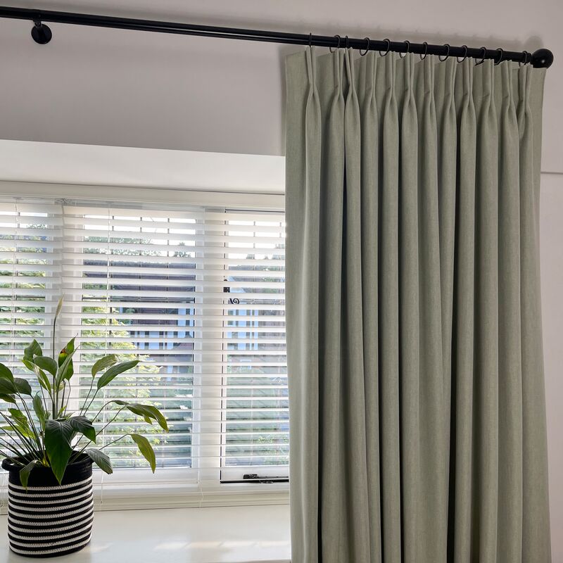 Pinch pleat curtain on a black pole pairs with wide white Venetian blinds, offering flexible light control and privacy at the window.