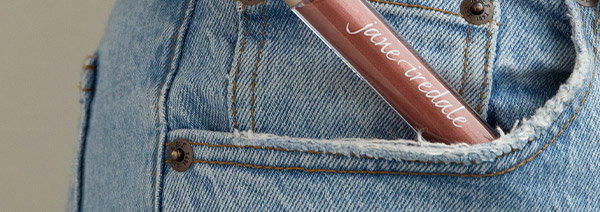 Hand pulling lip gloss from jean pocket