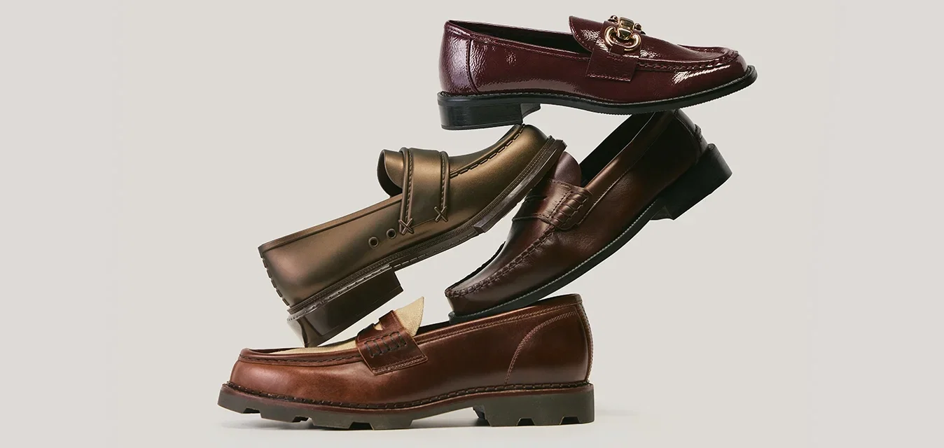 Vier paar lederen schoenen in verschillende tinten bruin en bordeaux, met zowel gladde als gestructureerde afwerkingen, asymmetrisch gestapeld.