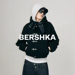 Jongere met een zwart jack, een grijze hoodie, donkere spijkerbroek en een zonnebril staand op een laag rollend platform tegen een effen achtergrond.