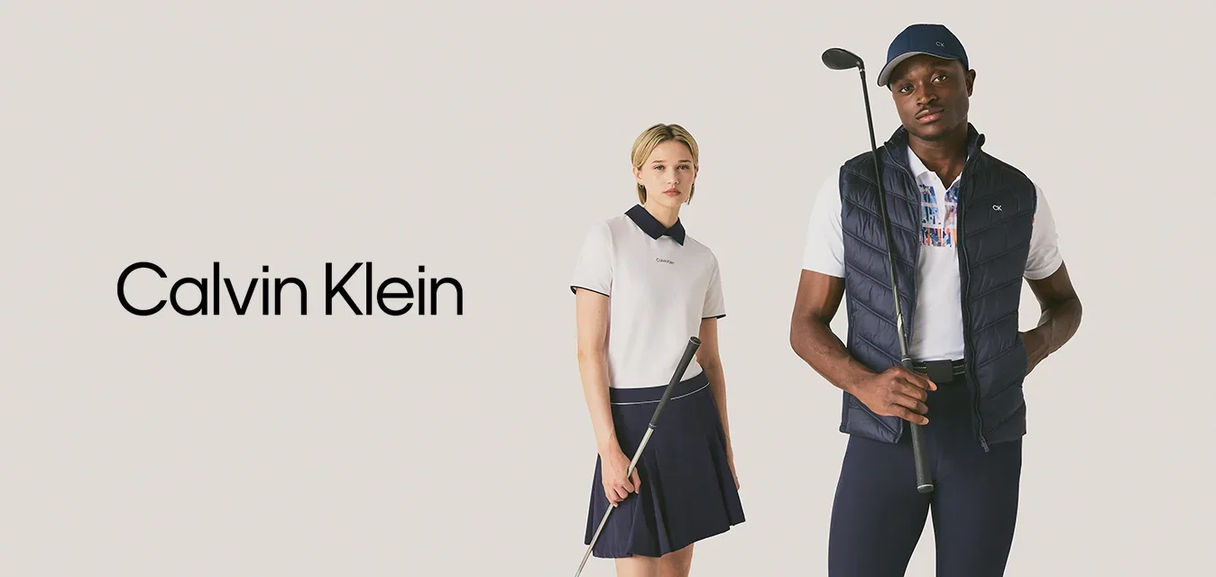 Twee jongvolwassenen staan met golfclubs gekleed in sportieve golfkleding tegen een effen achtergrond.