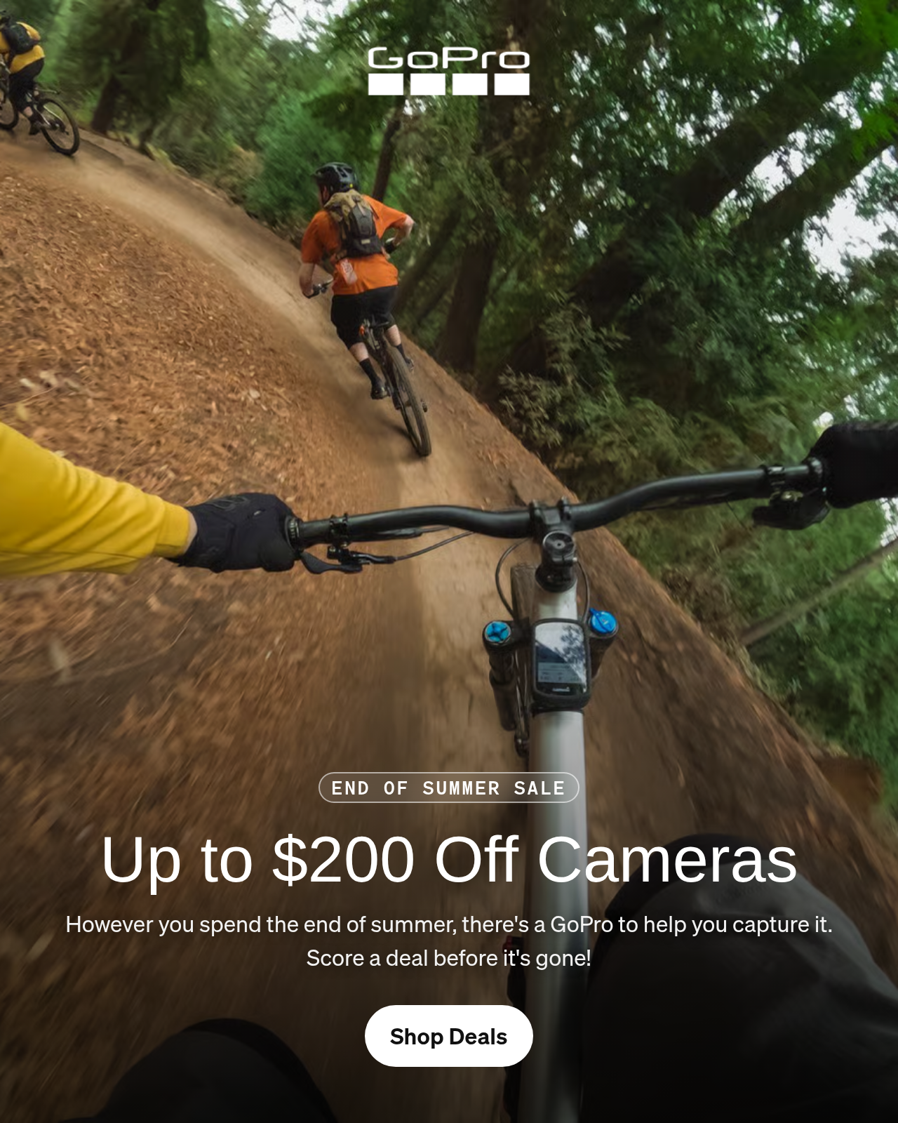 First-person view of three mountain bikers riding through a forest trail.