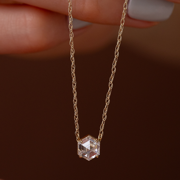 The Grand Prism Necklace shown against a dark brown background and held up by a model.