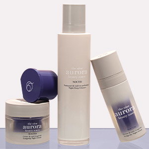 Frosted glass jar with its lid off sits besides cleanser bottle. The serum bottle leans at an angle on the right.
