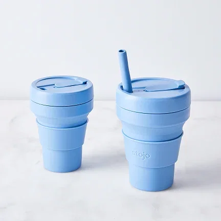 Two blue travel cups on a table.