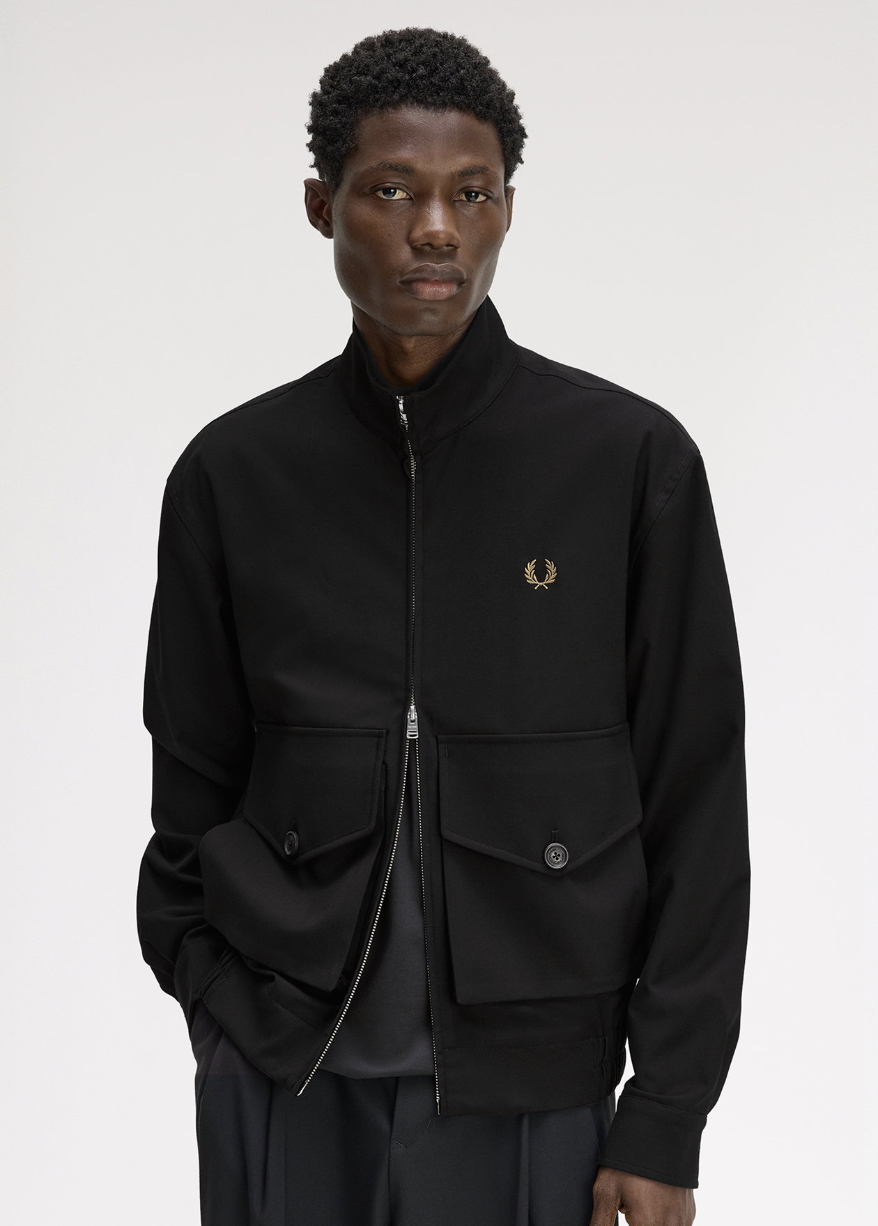 A male model wearing a Fred Perry Pocket Detail Zip-Through Jacket in Black Moss