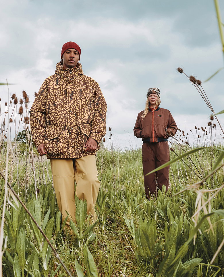 A man and a woman standing outside, wearing camo gear.