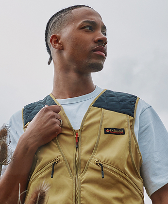 A man wearing a white short sleeve t-shirt and tan vest.
