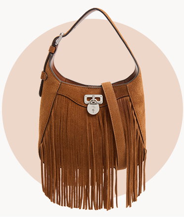 Tan suede shoulder bag with long fringe detailing and silver-tone hardware, displayed against a beige circular background.