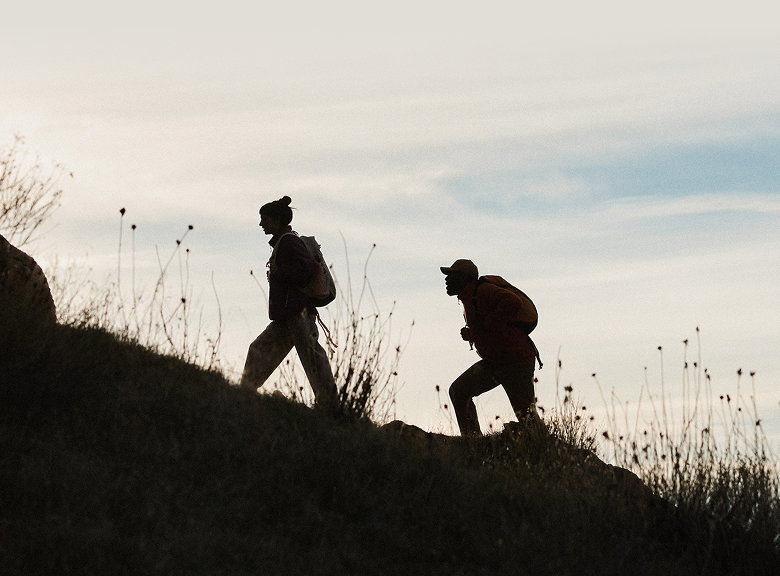 Silhouette of a man and women hiking up a mountain
