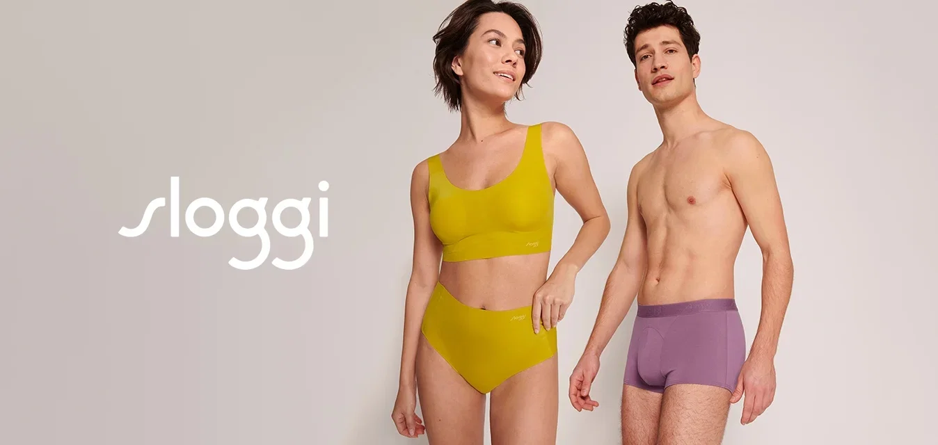 Geel sportbeha en bijpassende hoge slipjes, gecombineerd met paarse boxershorts, allemaal in een gladde stof met minimale naden, staand tegen een lichte achtergrond.