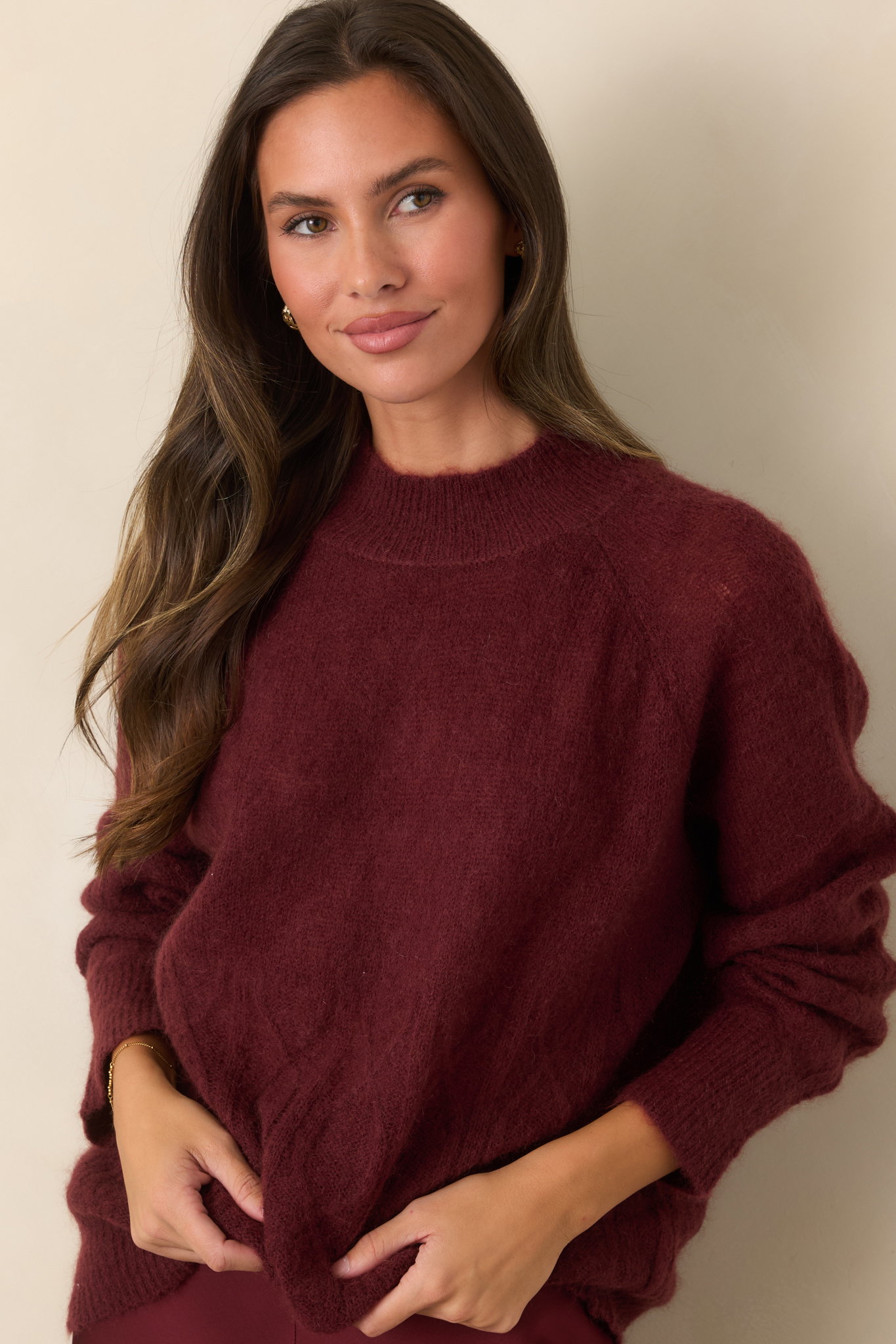 Model wearing a burgundy cable knit sweater.