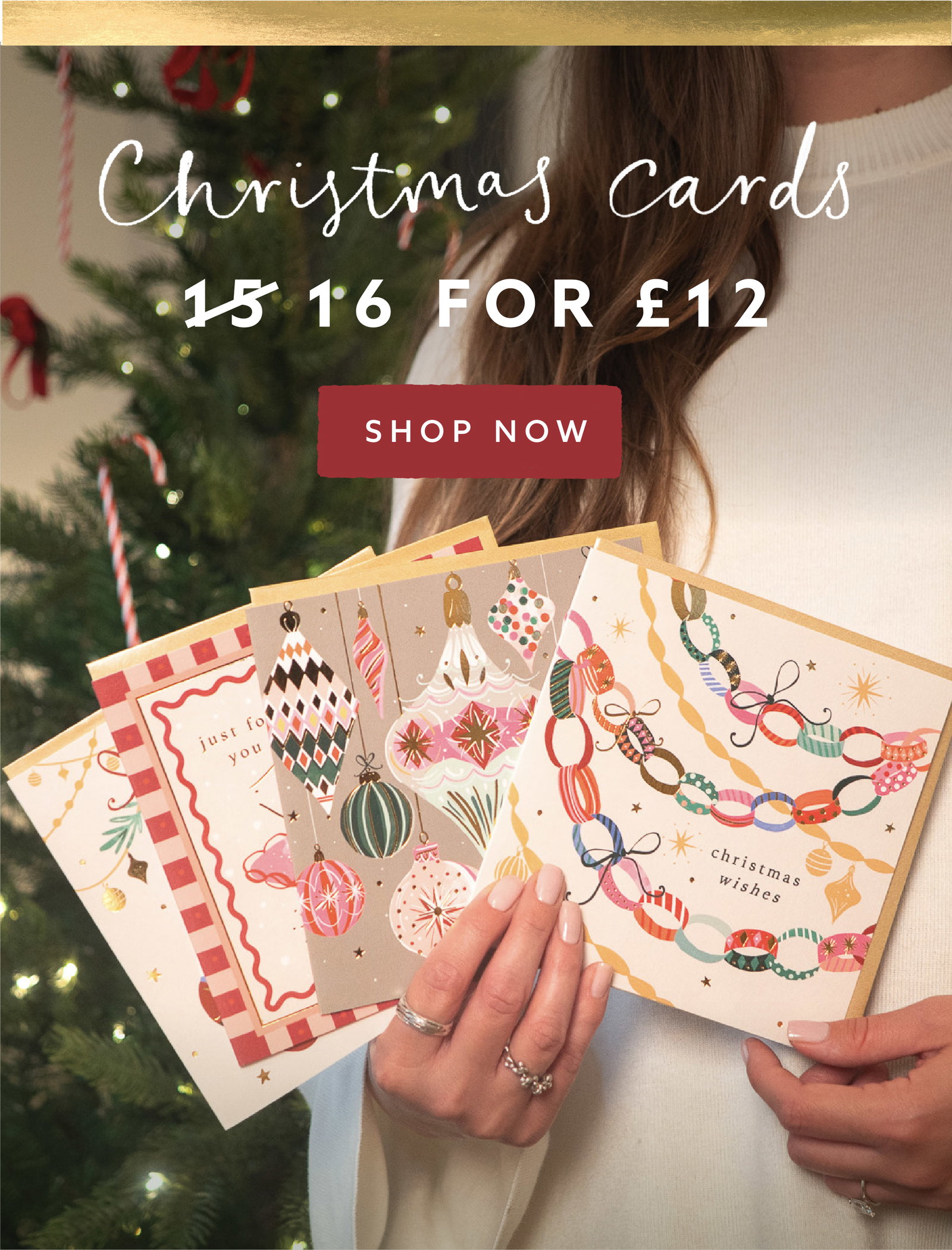 Woman holding a selection of colourful Whistlefish Christmas cards beside a decorated Christmas tree. Offer: choose 16 individual Christmas cards for £12.