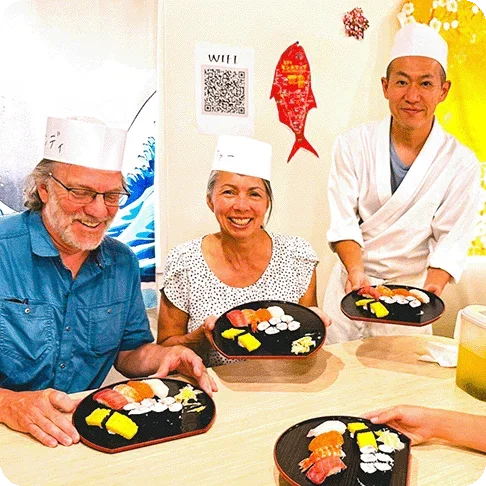 Image Description: Sushi making class with a couple and the instructor holding their plates of sushi to the camera.