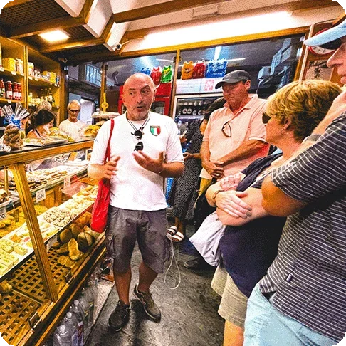 Image Description: Group food tour inside a bakery with the guide standing by the display case explaining something to the group.